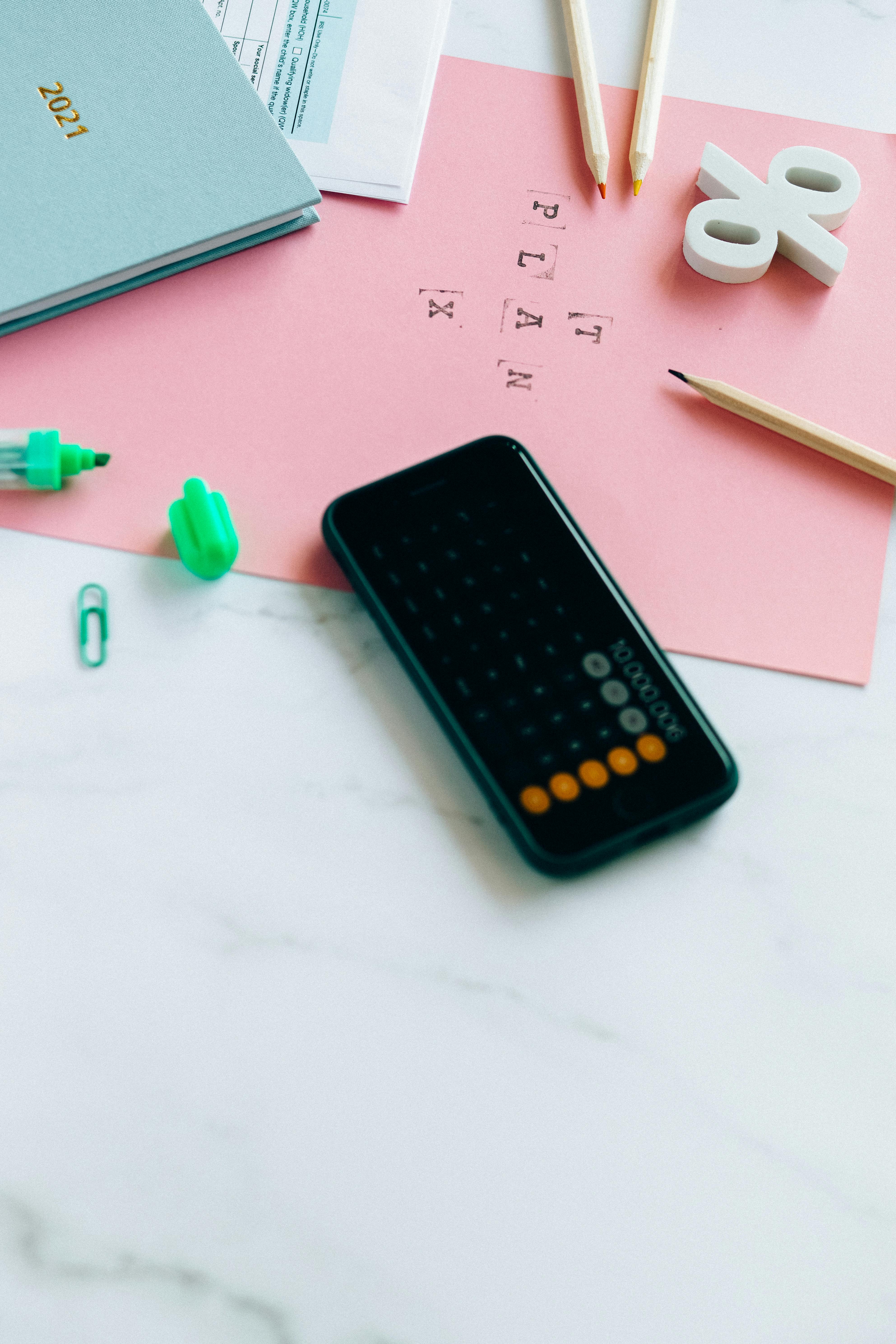 Aerial view of an office desk with a calculator, planner, and stationery.