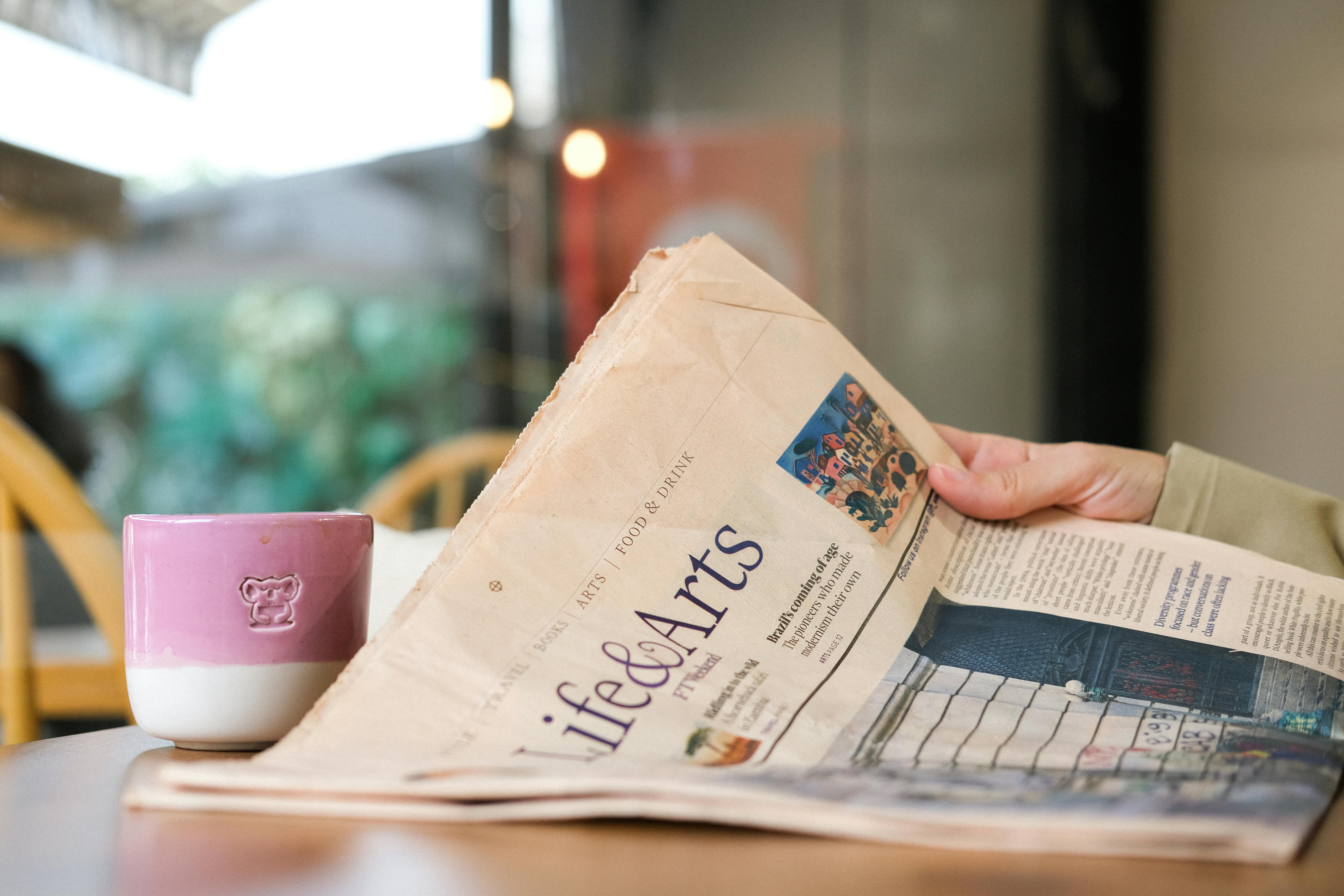 A person enjoying coffee while reading the Life & Arts section of the newspaper.